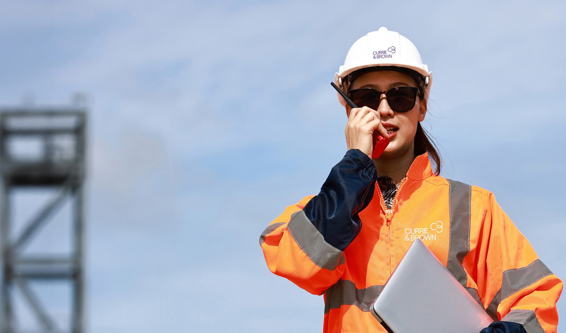 A woman holding a laptop on a construction site