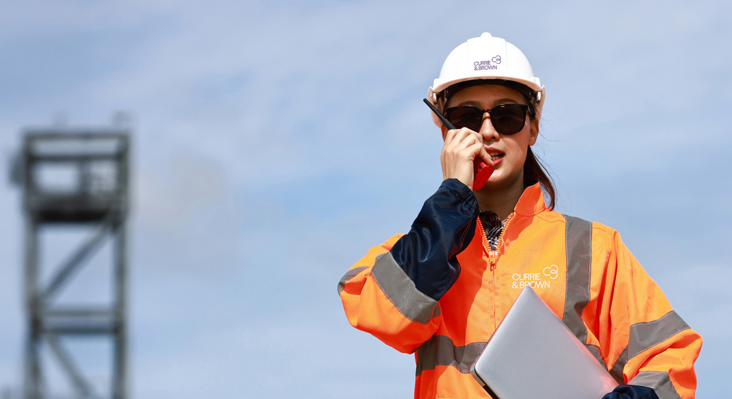 A woman holding a laptop on a construction site