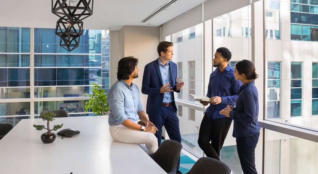 Four colleagues in a meeting room, having a discussion